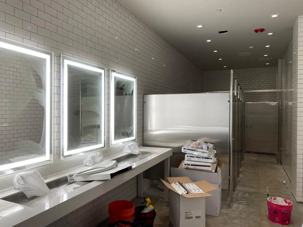 On-site Dynamic Electric Inc. buildout — recessed cans and lighted mirrors at rough finish